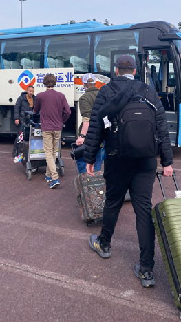 Student loading a passanger van with suitcases