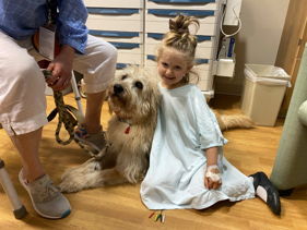 Girl in hospital gown with therapy dog