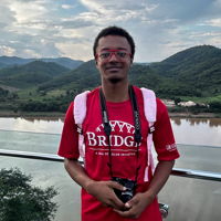 Cy holding a camera with mountains behind him in Khon Kaen, Thailand.