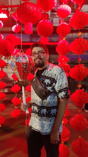 A USAC student stands beneath bright red lanterns in Thailand during a Chinese New Year celebration, holding a decorative lantern and smiling.
