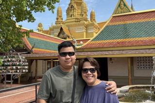 Two people standing in front of a Thai Wat in Chaing Mai, Thailand.