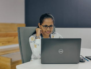 A young women smiling an working on a laptop