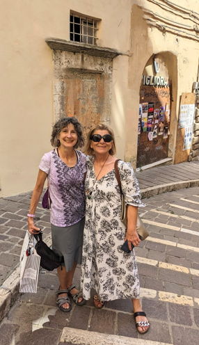 A USAC student and her Italian host mother smile together on a narrow stone street in Viterbo, Italy, surrounded by historic buildings.