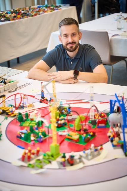 A facilitator beside a model built by the team