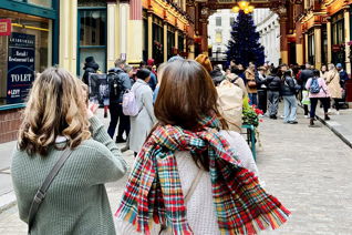 Two students with their backs to the camera exploring a holiday decorated street.