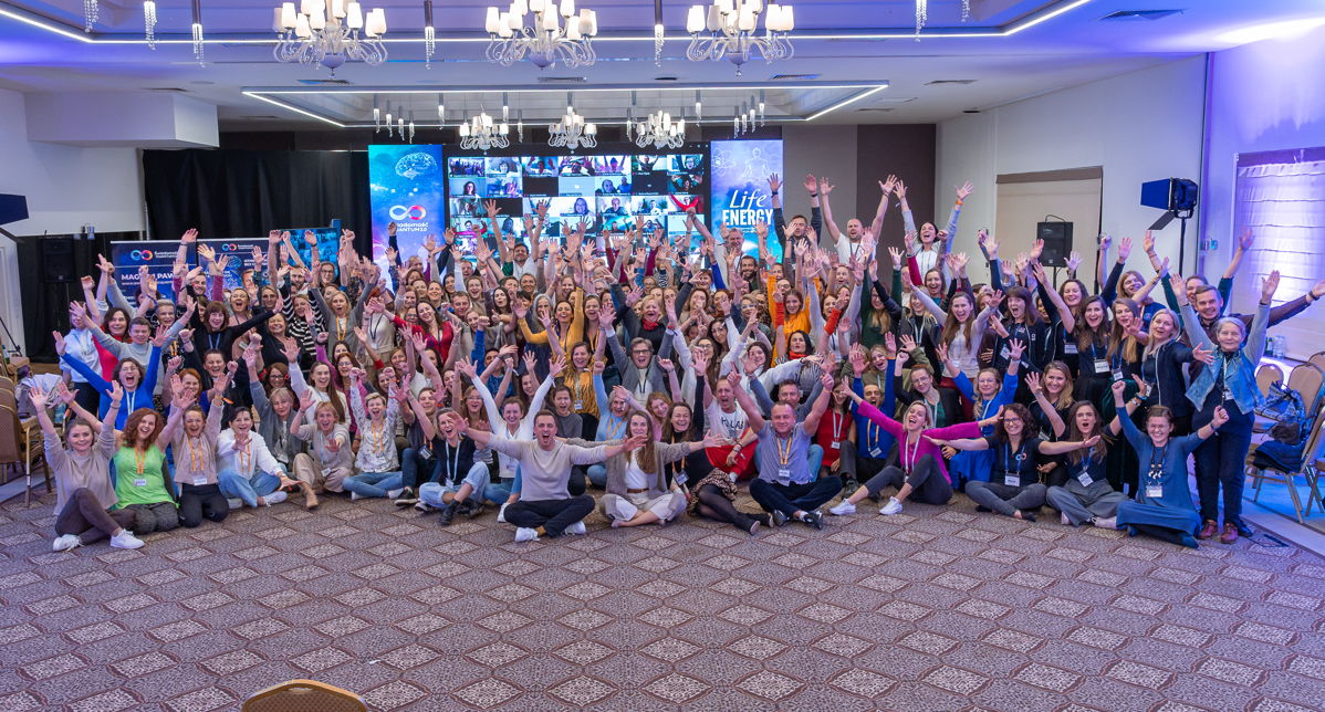 Cała grupa uczestników Life Energy z rękami w górze przed sceną