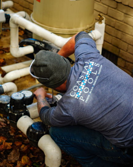 Coastal Pools technician working on pool pumps and plumbing