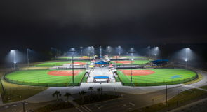 Home plate at recreational baseball field with two retrofitted LED light systems in the background