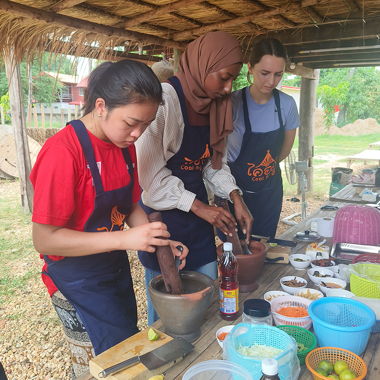 Three students making food in Thailand.