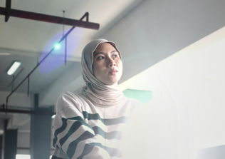 A women wearing a hijab looking towards the window where light gets in